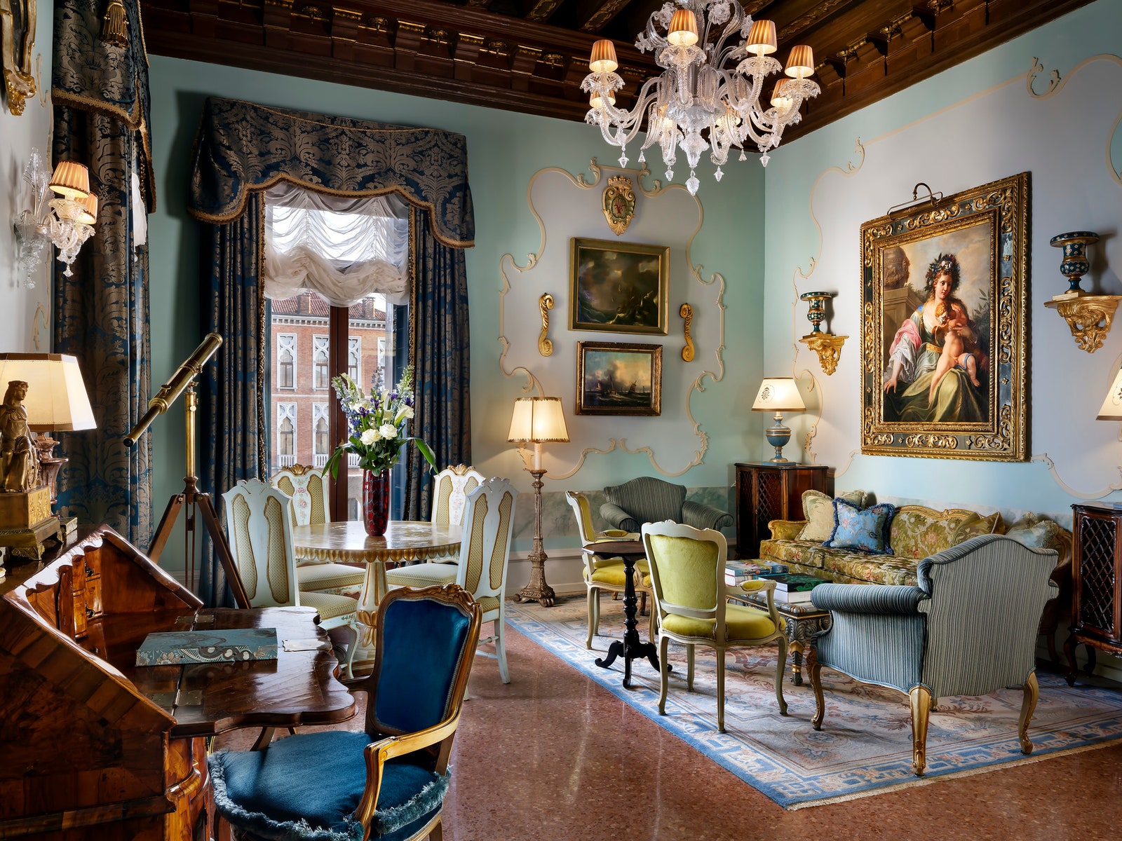 a luxurious hotel sitting room with blue and green furniture and a large chandelier